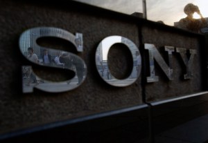 Pedestrians are reflected in a logo of Sony Corp outside its showroom in Tokyo